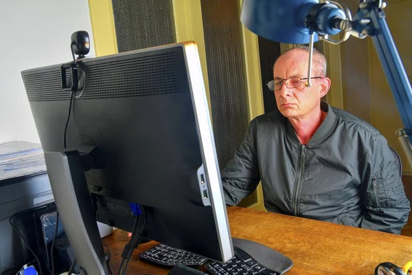 Orta masa başında oturan gözlüklü adam yaşlı. Kişisel bilgisayar kullanan olgun adam. Üst düzey kavramı. Ofiste çalışan adam. 