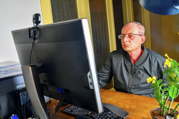 Orta masa başında oturan gözlüklü adam yaşlı. Kişisel bilgisayar kullanan olgun adam. Üst düzey kavramı. Ofiste çalışan adam. 