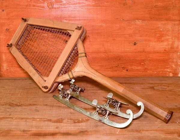 Vintage ice skates and tennis racket on wooden background. Retro ice skates and tennis racket. — Stock Photo, Image