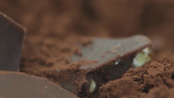 Chocolate, pedaços de chocolate escuro doce girado em pó de cacau, close-up. Rodado da direita para a esquerda. Ingrediente de sobremesa gourmet. Confeitaria, conceito de confeção. câmera lenta 4K UHD de vídeo . — Vídeo de Stock