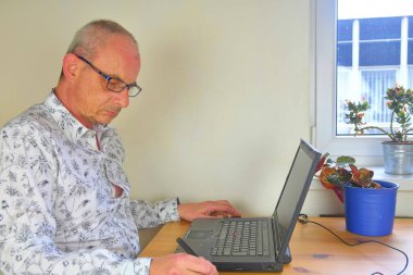 Merkez ofiste grafik tableti ve not defteriyle çalışan olgun bir adam.