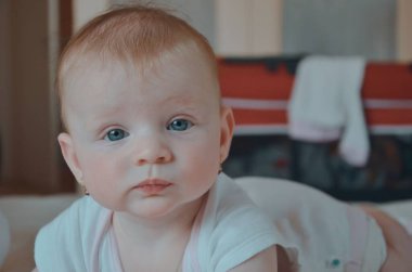 6 aylık tatlı bir gülümseme bebeğim. Yatak odasındaki yatakta bir kızın portresi. Ev içi oda. Evdeki yatakta emekleyen tatlı küçük kız.