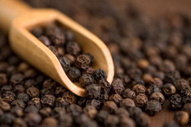 Karabiber veya ahşap bir arka planda ahşap kepçe içinde karabiber yakın çekim.