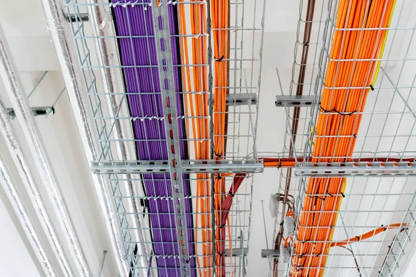 Electrical conduits system and metal pipeline installed on building ceiling. orange and purple wires