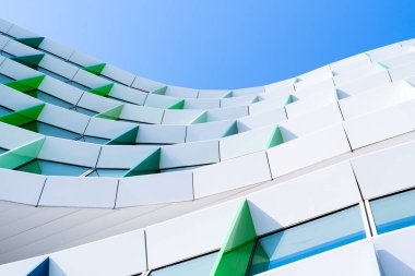 Renkli ofis binası, yeşil, mor ve mavi geometrik düzenle açılı pencere panelleri ile perade.