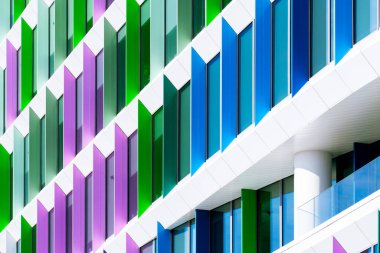 Renkli ofis binası, yeşil, mor ve mavi geometrik düzenle açılı pencere panelleri ile perade.