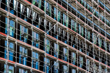 İnşaat halindeki ofis binası, cam perdelerini örten yapı iskelesi, gelişimi, ilerlemeyi ve kentsel dönüşümü sembolize ediyor..