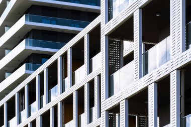 Camdan balkonları, delinmiş panelleri ve tekrarlayan geometrik ritmi olan yerleşim binaları modern şehir tasarımı yaratıyor..