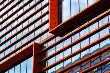 Açık pencereleri, güçlü simetrisi ve yansıtıcı gökyüzü detaylarıyla modern ofis binası..