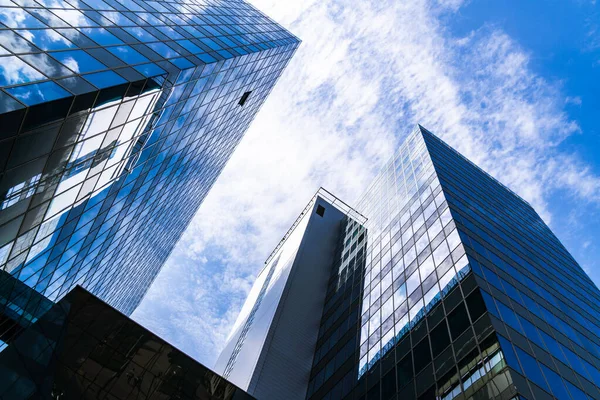 Pürüzsüz dikey çizgileri ve açık mavi gökyüzüne karşı yükselen cam perili modern yüksek katlı ofis kulesi..