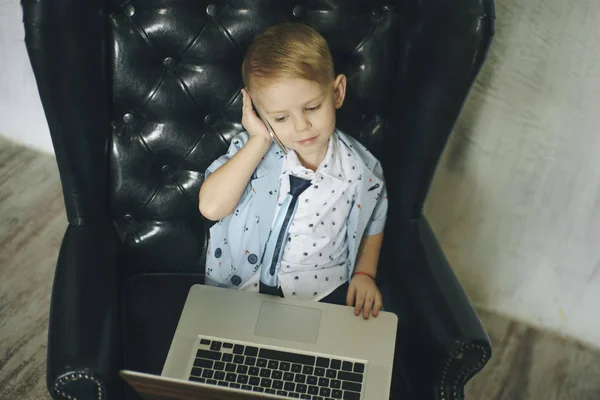 Jovem homem de negócios usando um laptop. Criança engraçada nos óculos. Retrato de moda de menino bonito no escritório — Fotografia de Stock