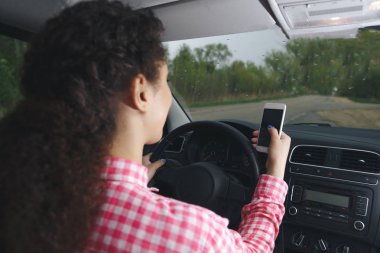 Kullanarak ve yolda bir araba akıllı telefon bakarak bir Asyalı