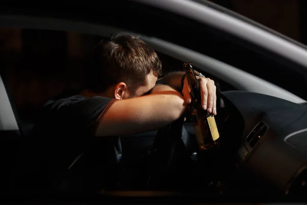 Conductor borracho bebiendo cerveza en el fondo de la iluminación del coche de la policía. Conducción bajo influencia del alcohol — Foto de Stock