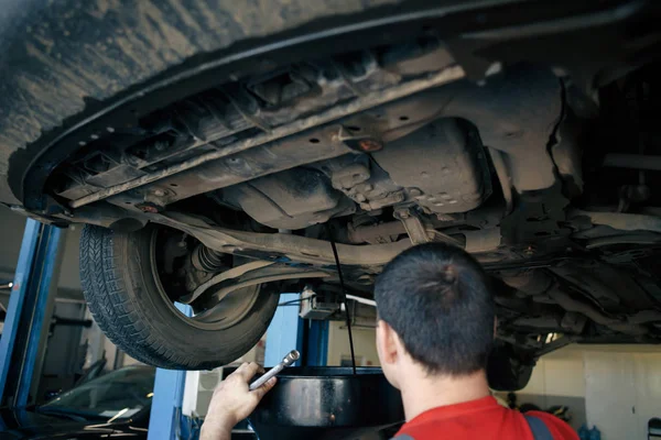 Mekaniker reparera bil med öppen huva, Sidovy över mekaniker kontroll nivå motorolja i en bil med öppen huva — Stockfoto