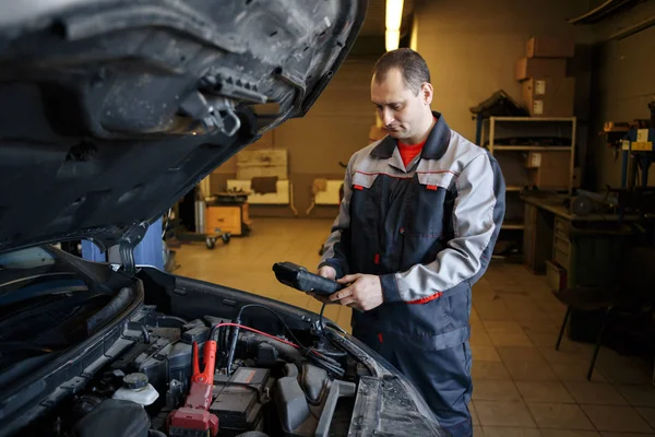 Cargador de batería y coche en taller de reparación de automóviles . — Foto de Stock