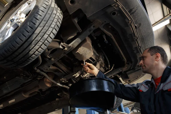 Profecional bilmekaniker byta motorolja i bilmotor underhåll reparation service station i en bilverkstad. — Stockfoto