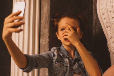 Bir cep telefonu ile koyu arka planda yatak odasında yatağın üzerinde oturan ağıt tutmak tek üzücü teen