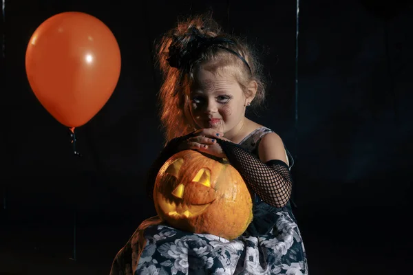 Fröhliche halloween süße kleine hexe mit einem kürbis. — Stockfoto
