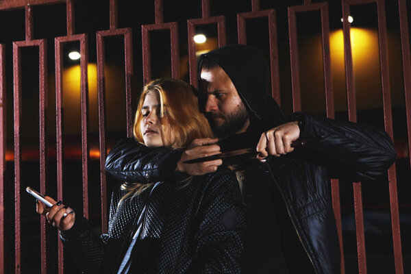 Kidnapper or Robber force knifepoint woman hostage to take off her clothes or steal her money at outdoors road. Raping sexual and Criminal theme. Social issues and problem concept