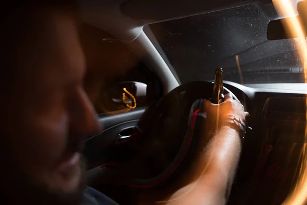 Rear view of a young man driving recklessly while drinking beer — Stock Photo, Image