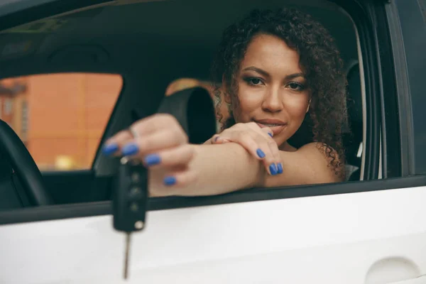 Щаслива жінка водій показує ключі від машини і спирається на двері автомобіля — стокове фото