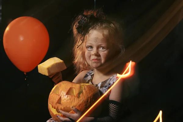 Lustiges Kindermädchen im Hexenkostüm zu Halloween mit Kürbiskerze und orangefarbenem Luftballon auf dunklem Hintergrund — Stockfoto