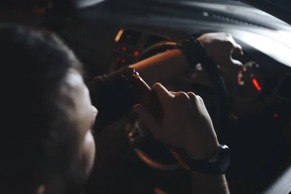 Пьяный молодой человек водит машину с бутылкой пива. Это фото кампании "Не пей за руль" — стоковое фото