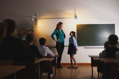 Yaşlı öğretmen öğrenci matematik dersine soran kara tahta yakınındaki gülümseyen