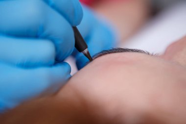 Kozmetik uzmanı kaşlarına kalıcı makyaj uyguluyor.