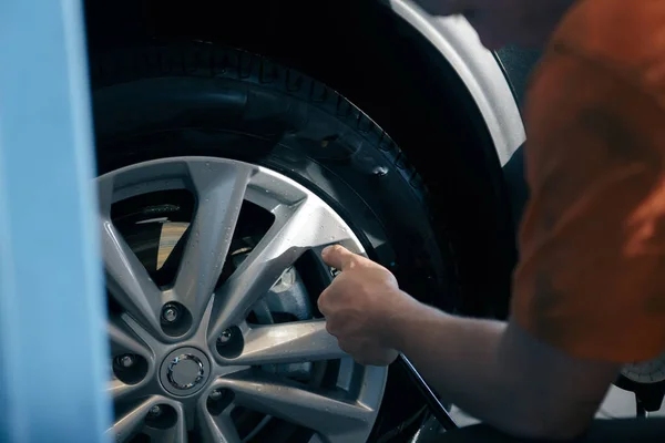 Auto mechanic man with electric screwdriver changing tire outside. Car service. Hands replace tires on wheels. Tire installation concept.