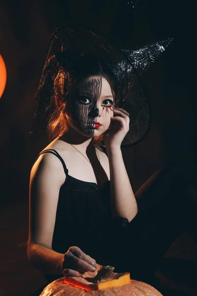 Happy Halloween leuk beetje heks met een grote pompoen. Mooie jonge kind meisje in heks kostuum buitenshuis. — Stockfoto
