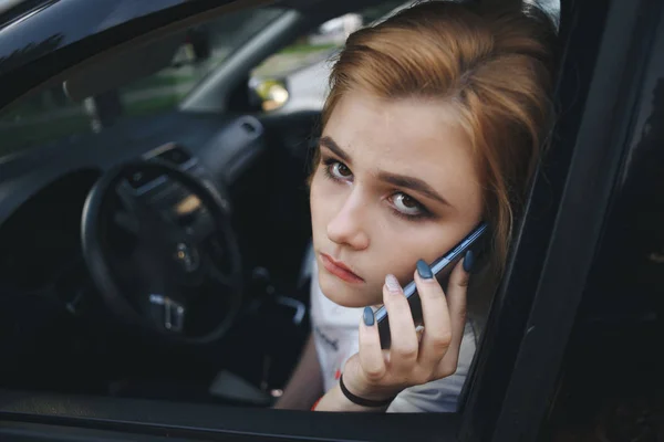 Дівчина сидить в машині розмовляє на мобільному телефоні — стокове фото