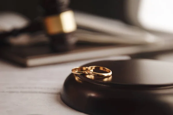 Cropped image of divorce judge hitting gavel on golden rings at desk in courtroom — Stock Photo, Image