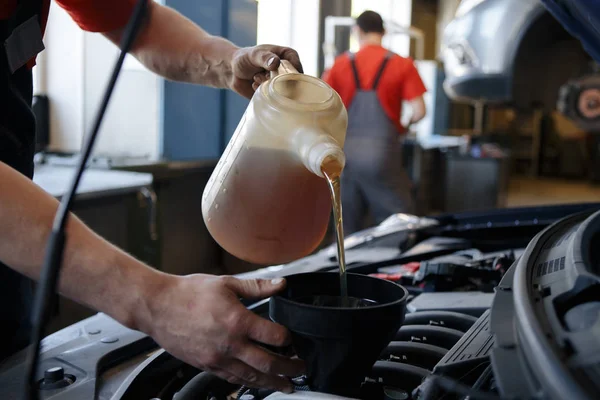 Mechanic pouring oil into car at the repair garage — Stock Photo, Image