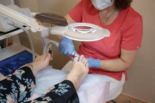 Tratamiento podológico. Podólogo tratando hongos en las uñas. El médico elimina callos, callos y golosinas uñas encarnadas. Manicura de hardware. Salud, concepto de cuidado corporal. Enfoque selectivo. — Foto de Stock