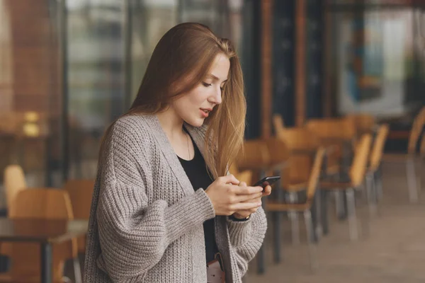 Bello donna sorridente con cellulare a piedi per strada — Foto Stock