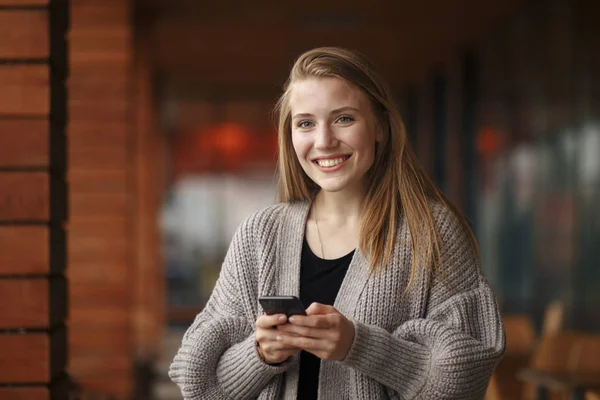 Giovane donna con shopping bag guardando il telefono nella soleggiata giornata autunnale . — Foto Stock