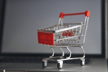 İnternetten alışveriş konsepti. Alışveriş arabası, küçük kutular, masadaki dizüstü bilgisayar.