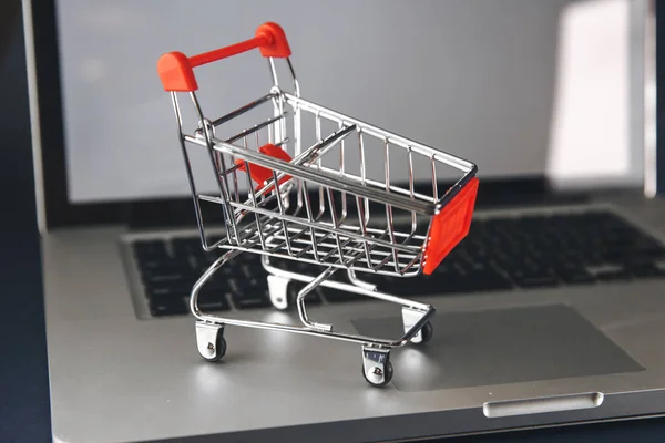 Concepto de compras online. Carro de la compra, cajas pequeñas, portátil en el escritorio — Foto de Stock