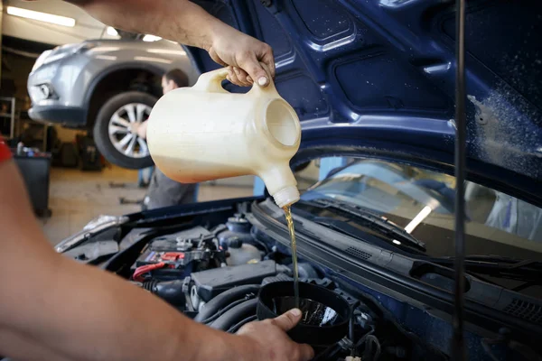 Car mechanic replacing and pouring fresh oil into engine at maintenance repair service station — Stock Photo, Image