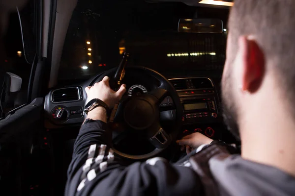 Drunk young man driving a car with a bottle of beer. Dont drink and drive concept. Driving under the influence. DUI, Driving while intoxicated. DWI — Stock Photo, Image