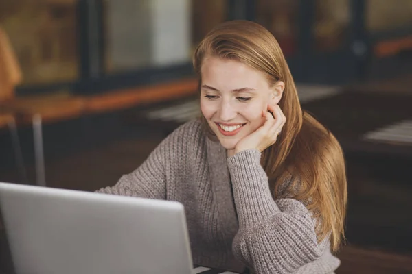 Diseñadora gráfica femenina exitosa viendo tutorial sobre ideas creativas en el ordenador portátil durante el proceso de trabajo en la oficina.Estudiante positiva con cabello rubio leyendo noticias de negocios en netbook — Foto de Stock