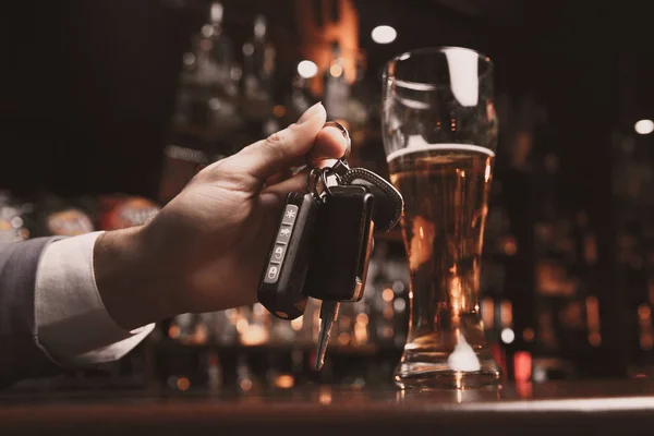 Jovem bêbado com um copo de cerveja e chave na mão — Fotografia de Stock