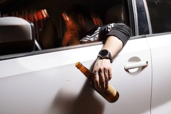 Young male driver drinking beer on the background of police car lighting. Man is caught driving under alcohol influence. — Stock Photo, Image