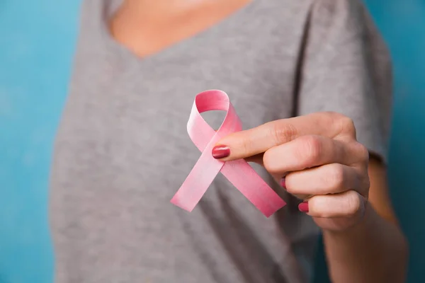 Womaen mano sosteniendo cinta rosa conciencia de cáncer de mama. concepto de asistencia sanitaria y — Foto de Stock