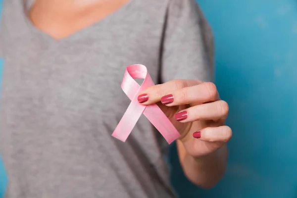 Womaen mano sosteniendo cinta rosa conciencia de cáncer de mama. concepto de asistencia sanitaria y — Foto de Stock