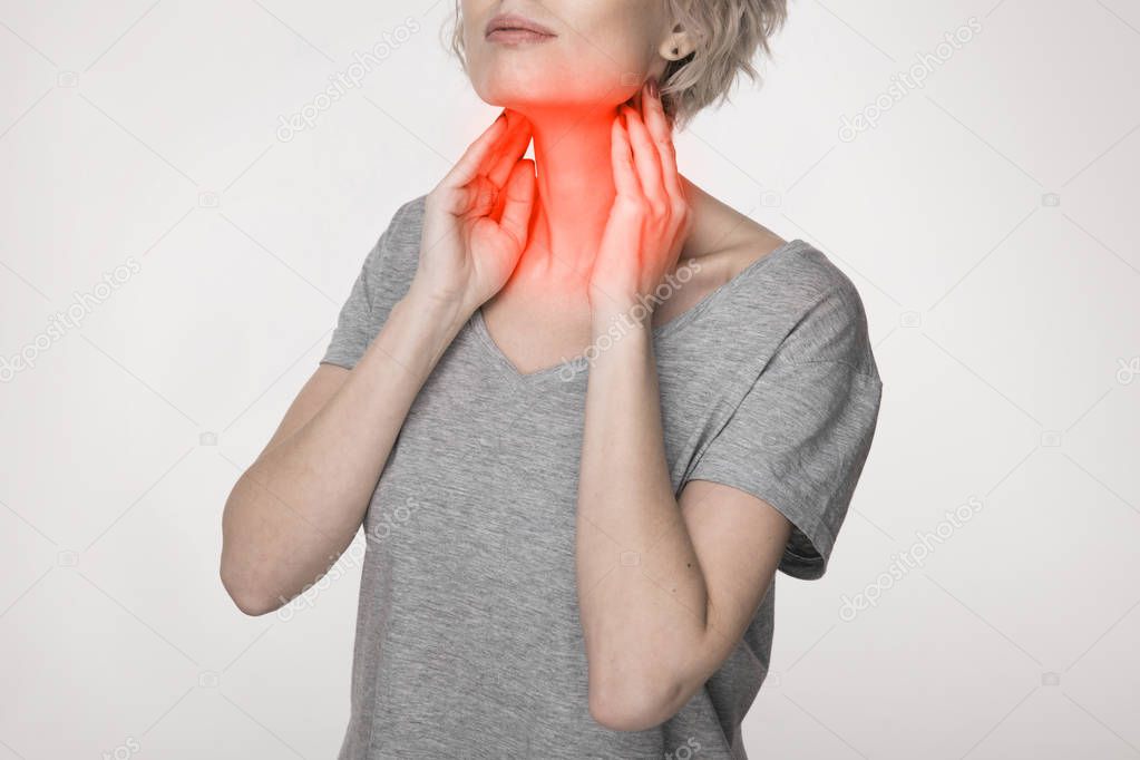 Female checking thyroid gland by herself. Close up of woman in white t- shirt touching neck with red spot. Thyroid disorder includes goiter, hyperthyroid, hypothyroid, tumor or cancer. Health care.