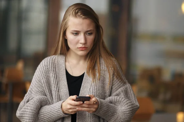 Primo piano ritratto divertente triste ragazza guardando pensando vedendo cattive notizie sms commento trolling messaggio foto telefono in mano disgustosa emozione sul viso isolato paesaggio urbano sfondo. Espressione umana — Foto Stock