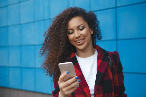 Bello donna sorridente con cellulare a piedi per strada — Foto Stock