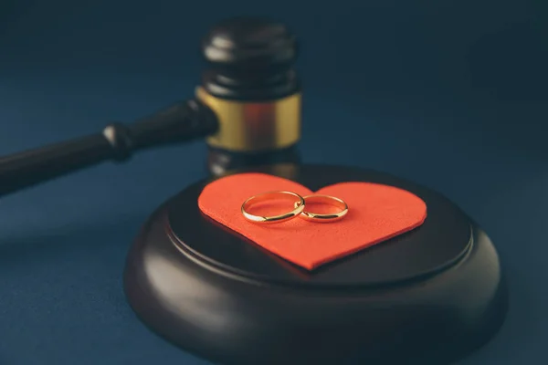 Wedding rings on the figure of a broken heart from a tree, hammer of a judge on a wooden background. Divorce proceedings — Stock Photo, Image